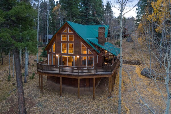 A wooden cabin with a balcony, surrounded by trees.