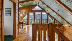 A wooden interior with a sloped ceiling, a staircase, and a view of the outdoors. - Dream Catcher Mountain View Cabin (Pigeon Forge)