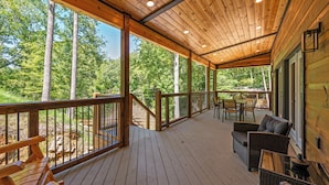 A wooden deck with outdoor seating and a view of a forest. - Ultimate Smoky Getaway: Hot Tub, Fun & Fresh Air in the Heart of the Smokies. (Sevierville)