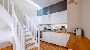 A modern kitchen with white cabinets, a wooden countertop, and a built-in oven. - Le Bijou du Minage - Jardin/terrasse - Hypercentre LA Rochelle (La Rochelle)