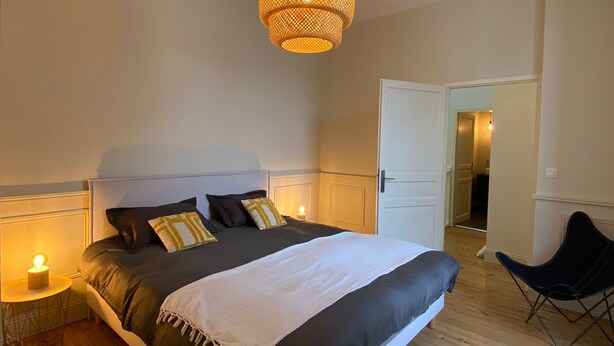 A bedroom with a bed, bedside lamps, a hanging light fixture, and a chair. - Le Bijou du Minage - Jardin/terrasse - Hypercentre LA Rochelle (La Rochelle)