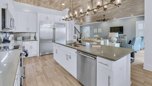 Una cocina moderna con armarios blancos, electrodomésticos de acero inoxidable y una isla central.