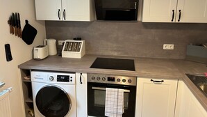 Una cocina compacta equipada con lavadora, horno, microondas y tostadora.