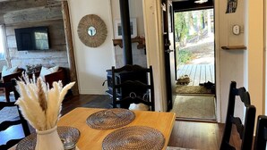 A cozy living room with a fireplace, a television, and a dining area with a wooden table and woven placemats.