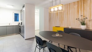 Eine moderne Küche mit grauen Schränken, einer gelben Arbeitsplatte und einem Essbereich mit dunklem Tisch und Stühlen.