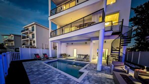 A modern two-story building with a swimming pool, outdoor seating, and a spiral staircase. - Beach One: Style Meets the Shore w/ Pool and Spa (Treasure Island)