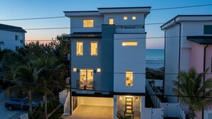 A modern multi-story building with balconies, a staircase, and a view of the ocean. - Beach One: Style Meets the Shore w/ Pool and Spa (Treasure Island)