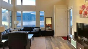 Ett modernt vardagsrum med en soffa, en tv och ett stort fönster med utsikt över ett vackert landskap.