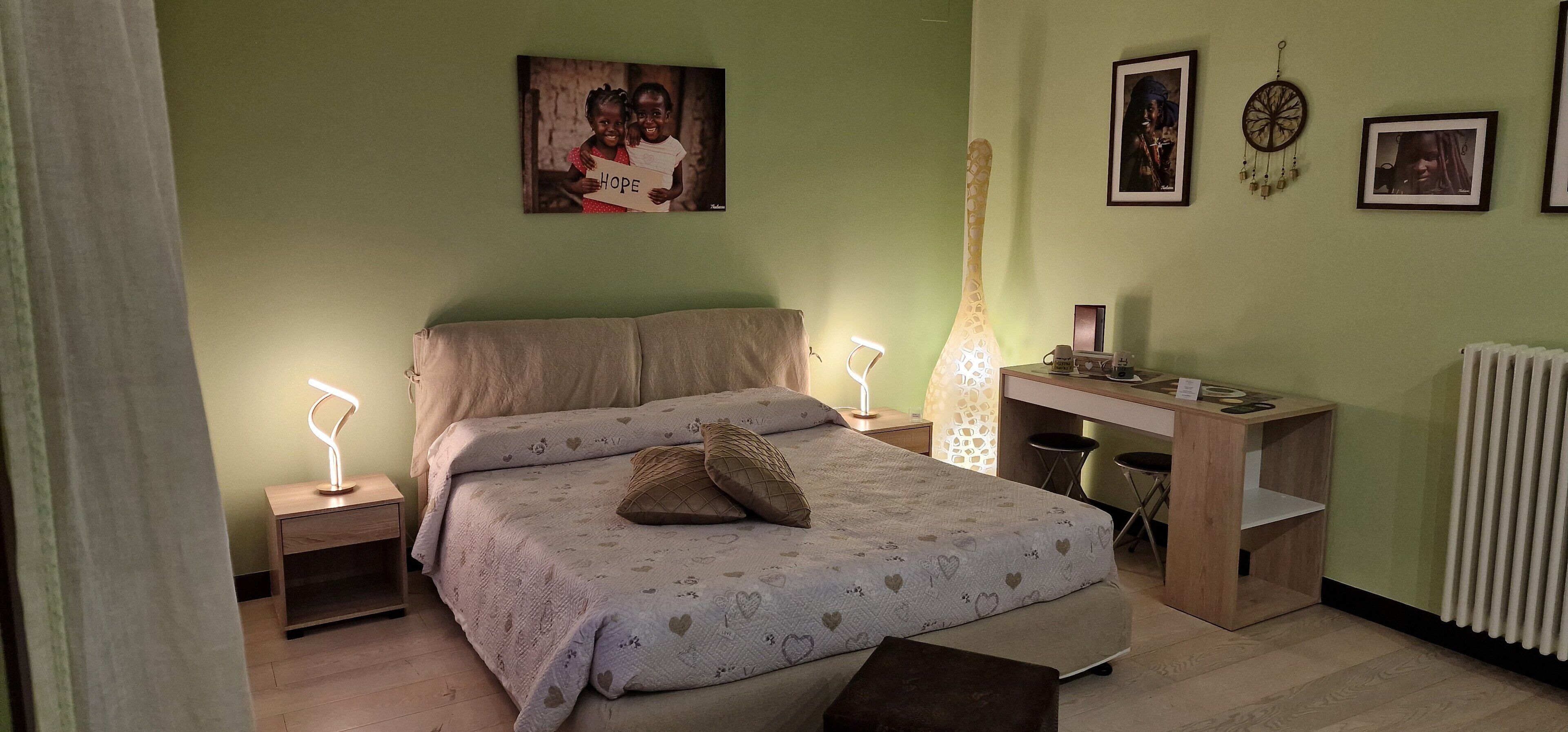 Une chambre à coucher comprenant un lit, des tables de chevet, un bureau et une étagère fixée au mur.