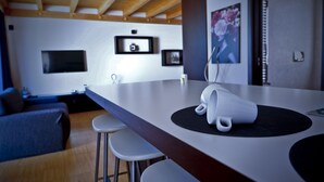 A modern kitchen with a large island, bar stools, and a flat-screen TV mounted on the wall. - Thalassa Bari (Bari)