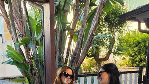 Two people seated at a table with a vase of flowers, under a wooden pergola with plants in the background. - Thalassa Bari (Bari)