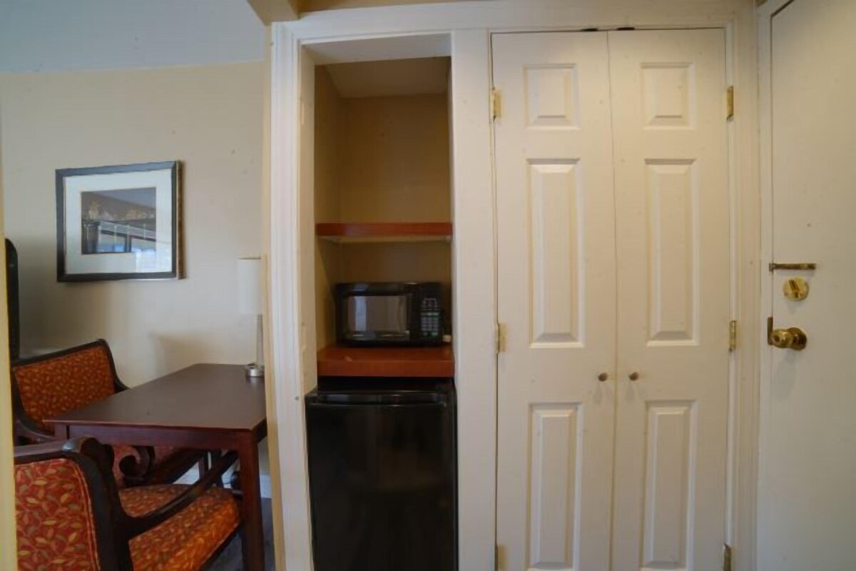 A compact kitchen with a microwave, refrigerator, and a dining area with a table and chairs.