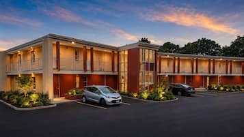 Un hotel de varios pisos con estacionamiento, que presenta un diseño arquitectónico moderno con elementos de ladrillo y vidrio.