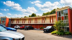 Un motel con diversi posti auto e un edificio dalle tonalità di rosso e beige.