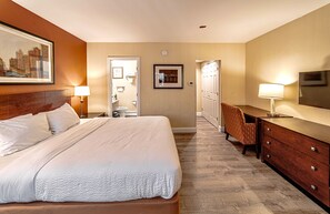 A hotel room with a large bed, a desk with a chair, a television, and a door leading to a bathroom. - Hotel Boston (Boston)
