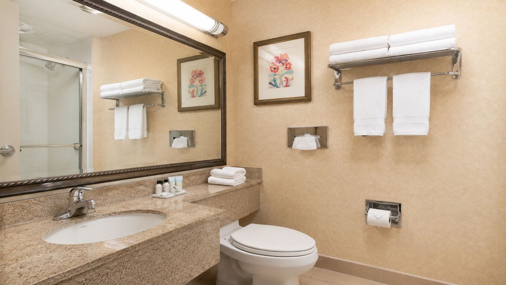 Un baño con lavamanos, inodoro y toalleros.