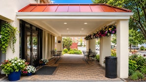 A covered outdoor seating area with tables and chairs, surrounded by potted plants and flowers. - The Boston Hotel  (Boston)