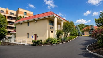 A two-story building with a red roof, a wheelchair-accessible entrance, and a paved driveway.