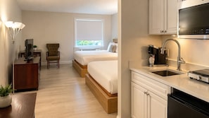 A hotel room with a bed, a desk, a chair, a window, and a kitchenette. - The Boston Hotel  (Boston)