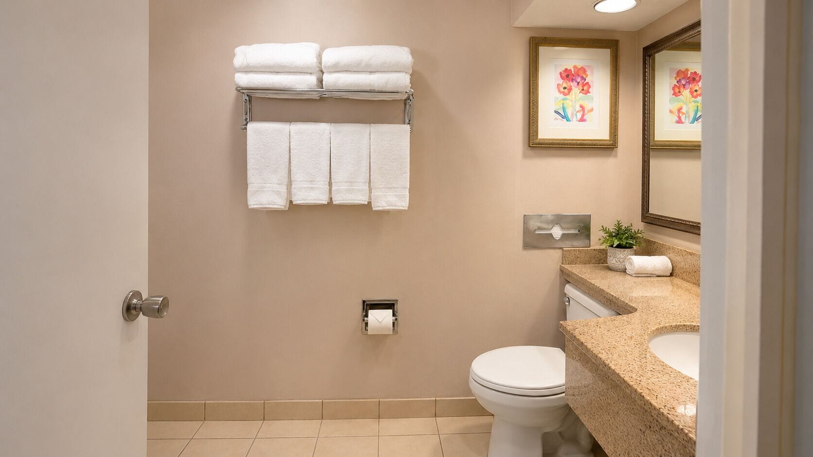 A bathroom with a toilet, sink, towel rack, and framed artwork on the wall.