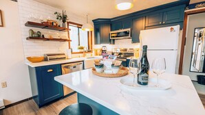 Een moderne keuken met een marmeren aanrechtblad, inbouwapparatuur en een centraal kookeiland met zitplaatsen.