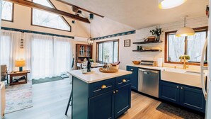 Een moderne keuken met donkerblauwe kastjes, een centraal eiland en een inbouwoven.