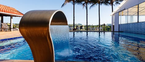 Una piscina techada, una piscina al aire libre, sombrillas