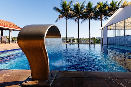 Una piscina techada, una piscina al aire libre, sombrillas