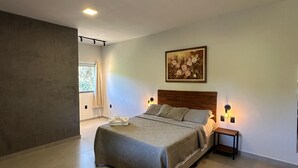 Une chambre à coucher moderne avec un grand lit, un tableau au mur et une petite table de chevet avec une lampe.