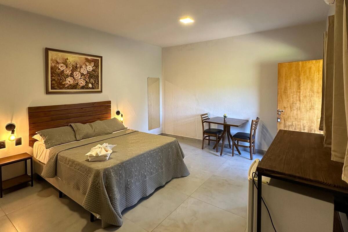 Un dormitorio con cama, mesitas de noche, un escritorio y una silla.