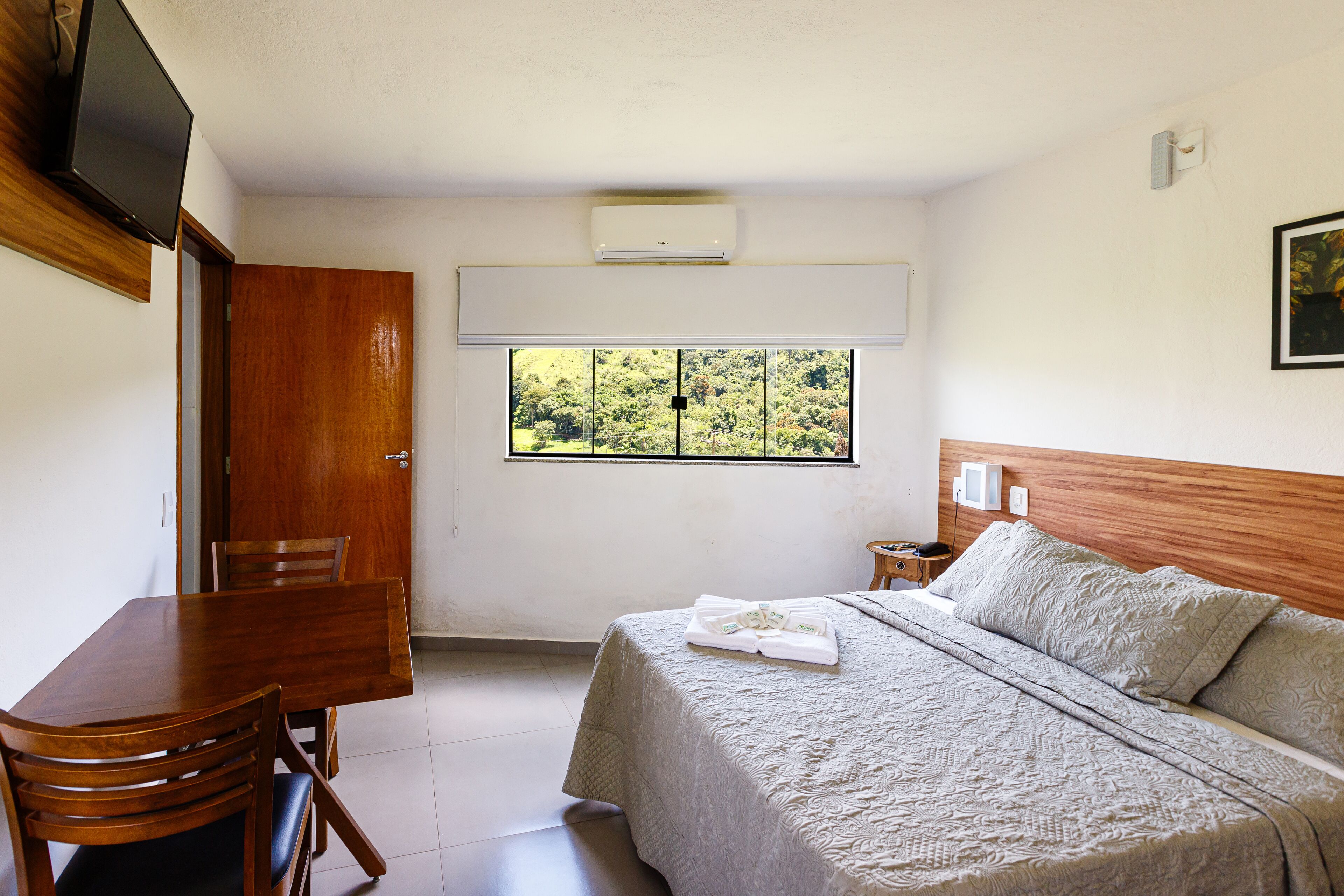 Una camera da letto con un letto, un tavolo di legno e una TV.