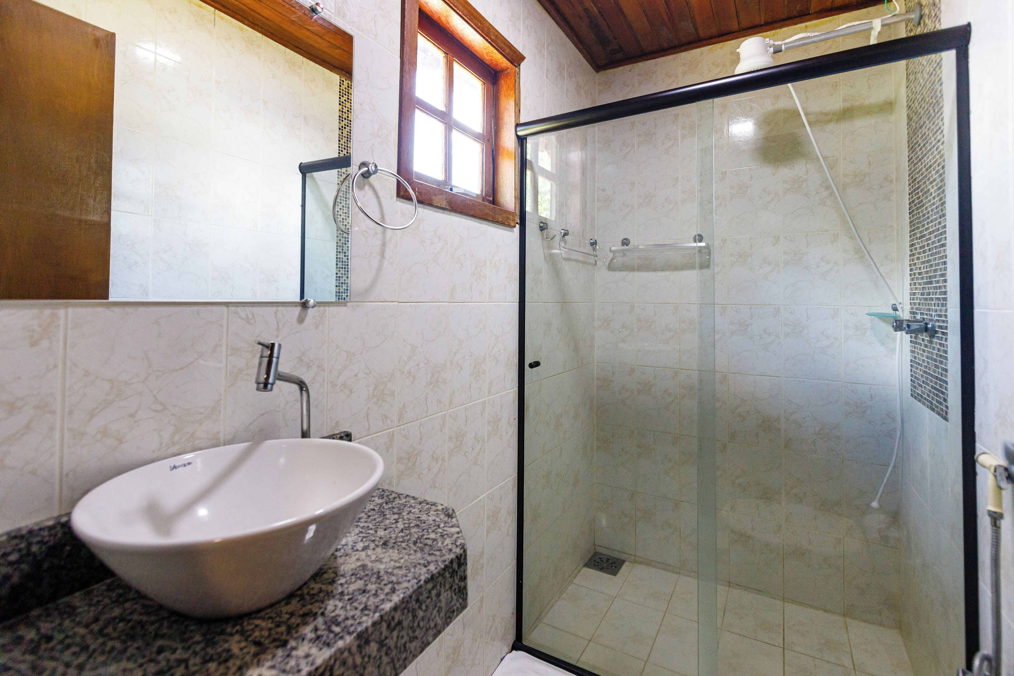 A bathroom with a white sink, a glass shower enclosure, and a wooden ceiling.