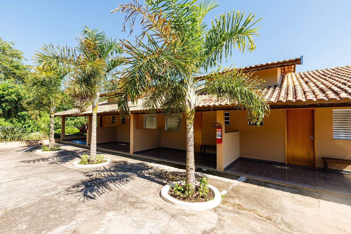 Un edificio con tejado de baldosas, un espacio al aire libre cubierto y varias palmeras.