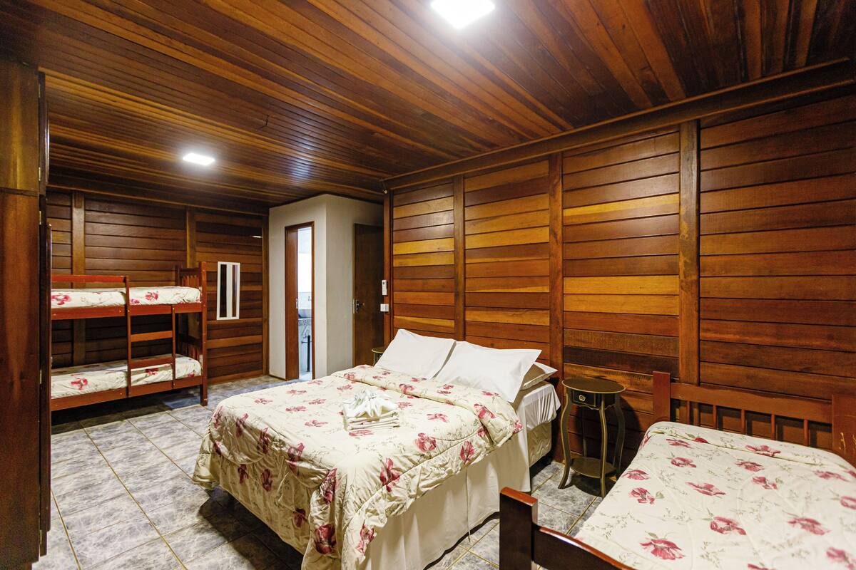 Una habitación con paneles de madera, literas y una cama individual.