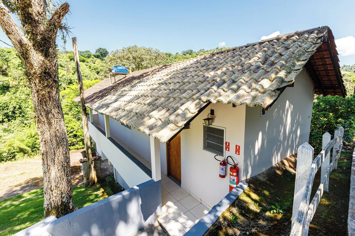 Una casa pequeña con techo de tejas, puerta de madera y un extintor instalado en la pared.