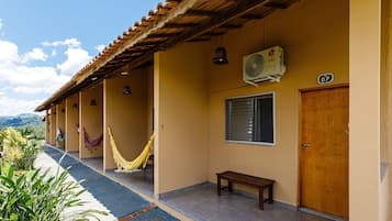 A building with a tiled roof, a bench, a hammock, and a door marked with the number 07.