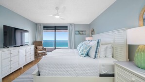 A bedroom with a large bed, a TV, a dresser, and a view of the ocean. - 🌞CBC 2-11B | Gulf-view 2BR/2BA condo on Clearwater Beach with pool & tennis! (Clearwater Beach)