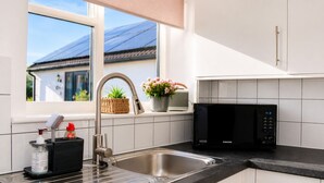 A modern kitchen with a stainless steel sink, a black microwave, and white cabinets. - Lodge 1 - Lytton Tree Lodge - Reydon (Reydon)