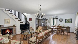 Un salón amplio con chimenea, televisor, comedor y escalera.