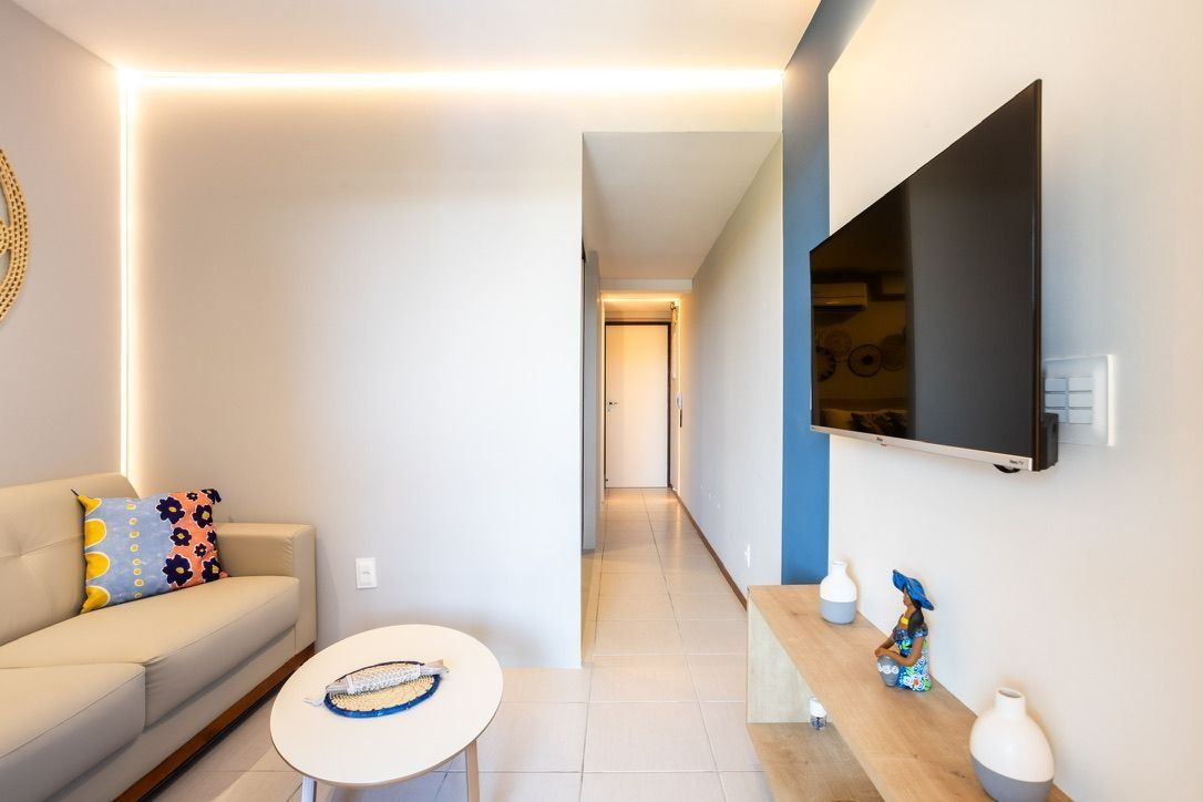 Un salon moderne avec un canapé, une table basse et un téléviseur à écran plat fixé au mur.