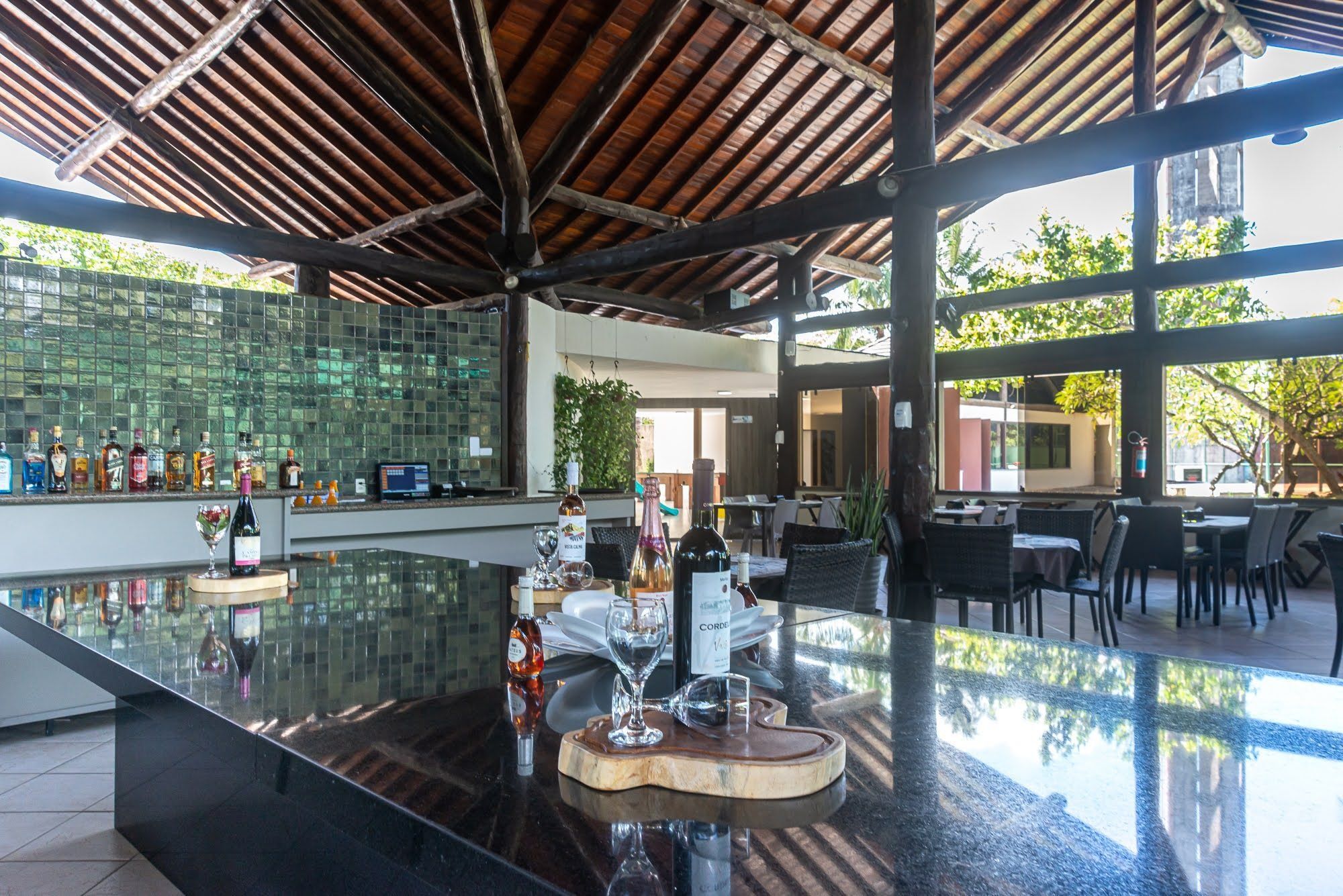Una zona de bar con mostrador de cristal, varias botellas y vasos.
