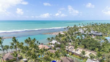 Un resort con vista a la playa, múltiples piscinas y un cielo despejado.