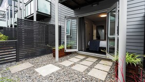 Una casa moderna con ingresso tramite porta scorrevole in vetro, un vialetto in pietra e una recinzione nera.