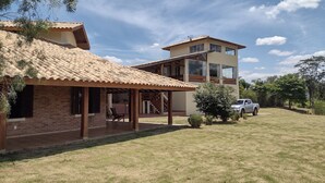 Una casa de dos pisos con un patio y un automóvil estacionado en la entrada.