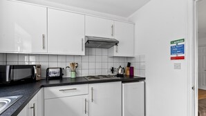 A modern kitchen with white cabinets, a stainless steel range hood, a microwave, a toaster, and a dishwasher.