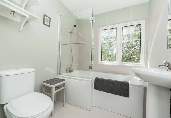 A modern bathroom with a glass-enclosed shower, a toilet, a sink, and a window providing natural light. - Wonderful thatched cottage in The New Forest (Minstead)