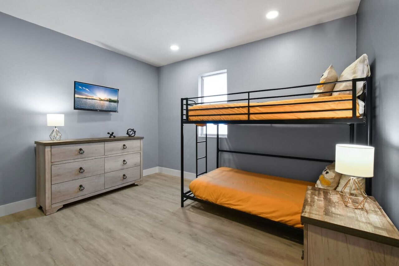 Une chambre avec un lit superposé, une commode, un téléviseur et une fenêtre.