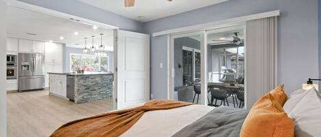 Une chambre d’hôtel moderne dotée d’un grand lit, d’un ventilateur de plafond et offrant une vue sur la cuisine et l’espace repas.