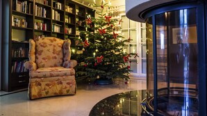 A cozy living room with a floral armchair, a Christmas tree, and a fireplace.