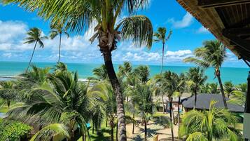 Un resort tropical con palmeras, vista a la playa y una estructura de techo de paja.